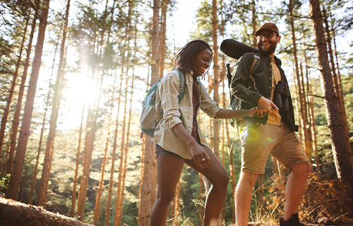 Man and Woman Hiking through Woods Holding Hands